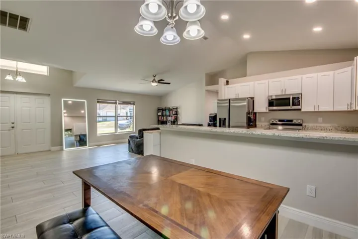 Dining area with a chandelier, lofted ceiling, wood finish floors, and a ceiling fan