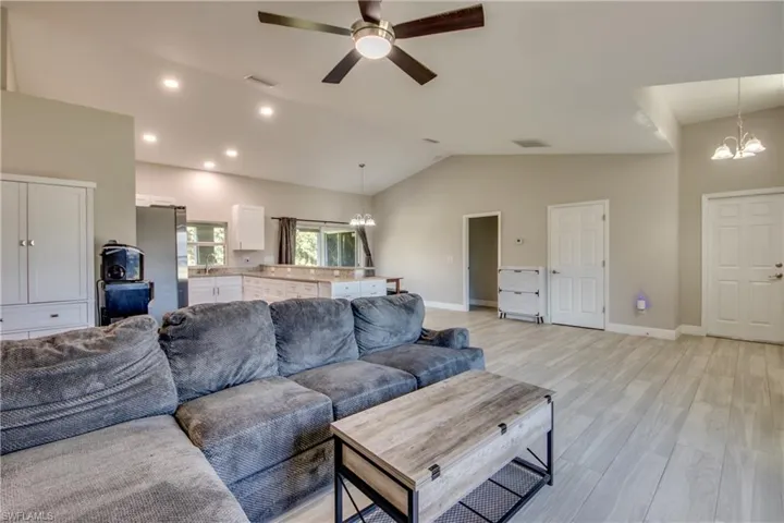 Living room with a chandelier, vaulted ceiling, light wood-type flooring, a ceiling fan, and recessed lighting
