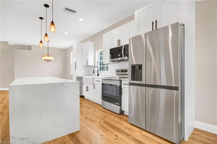 Kitchen with white cabinets, visible vents, a sink, and appliances with stainless steel finishes