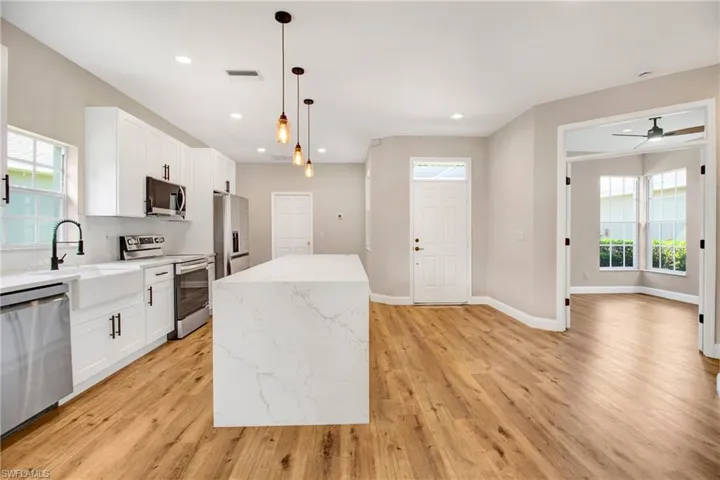 Kitchen with a center island, plenty of natural light, light wood-style flooring, and appliances with stainless steel finishes