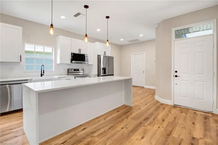 Kitchen with light wood finished floors, stainless steel appliances, a sink, visible vents, and backsplash