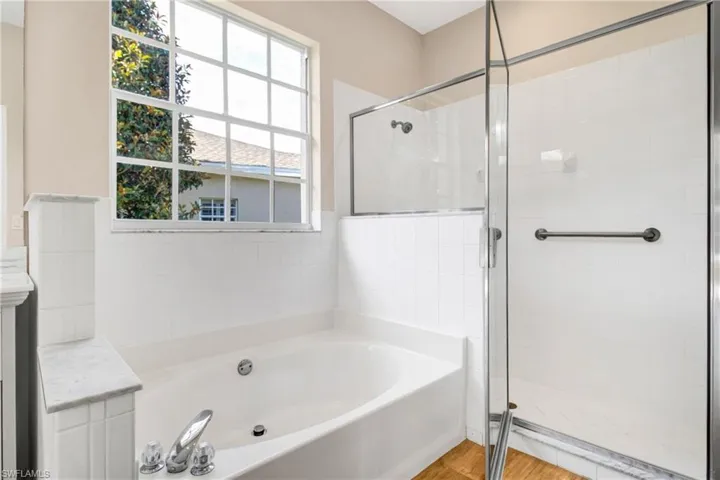 Full bath with a garden tub, wood finished floors, and a shower stall