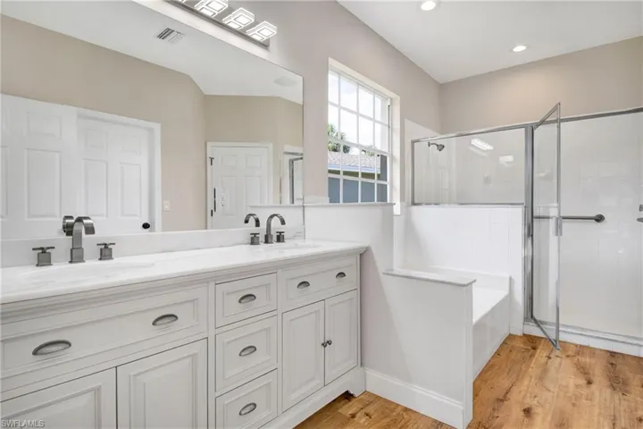 Full bath featuring double vanity, a shower stall, wood finished floors, and a sink