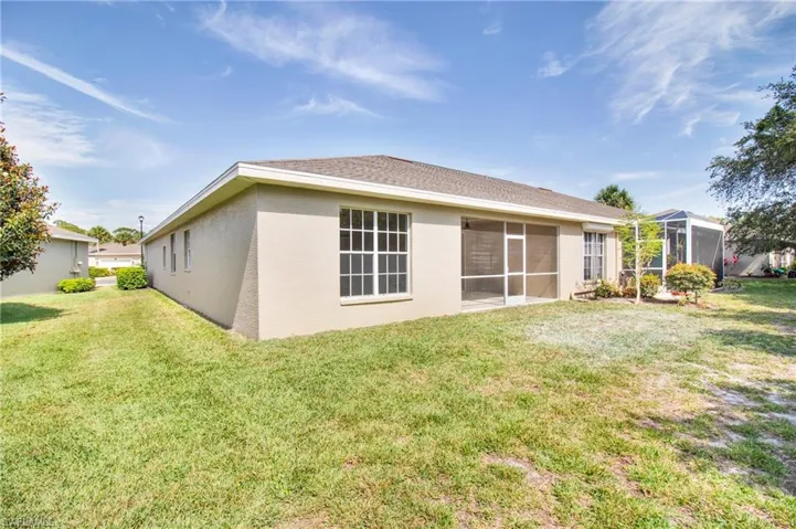 Back of house with stucco siding and a yard