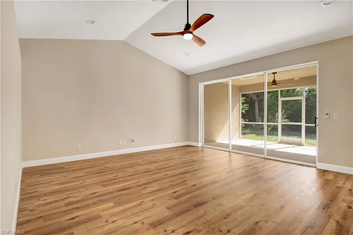 Unfurnished room with lofted ceiling, baseboards, wood finished floors, and ceiling fan