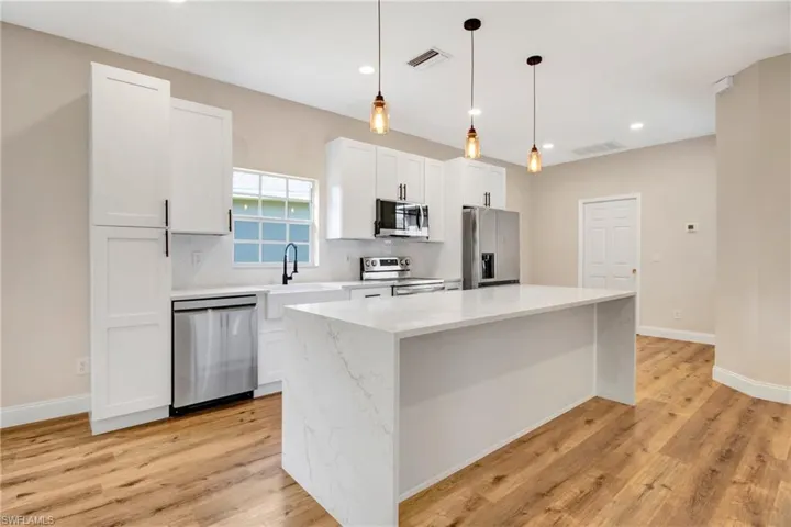 Kitchen with stainless steel appliances, a center island, visible vents, and tasteful backsplash