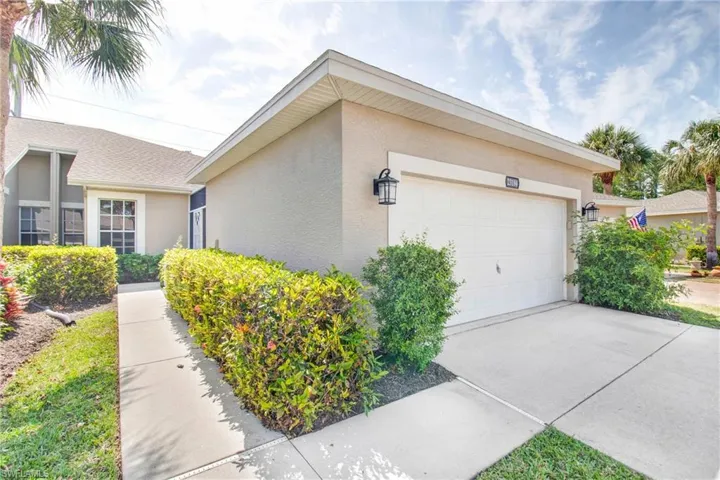 View of side of home featuring an attached garage, concrete driveway, and stucco siding