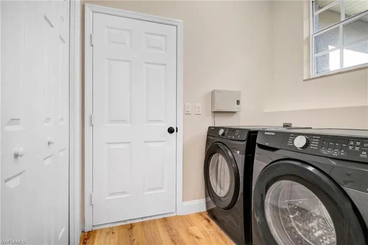 Laundry room featuring separate washer and dryer, baseboards, light wood-style floors, and laundry area