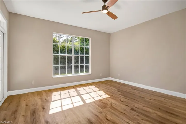 Spare room featuring wood finished floors, a ceiling fan, and baseboards