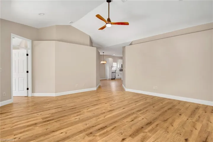 Unfurnished living room featuring high vaulted ceiling, baseboards, a ceiling fan, and light wood-style floors