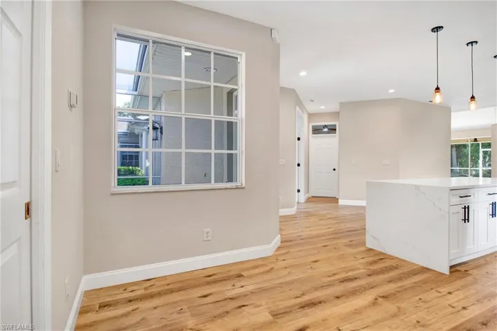 Kitchen featuring light wood finished floors, baseboards, recessed lighting, white cabinetry, and pendant lighting