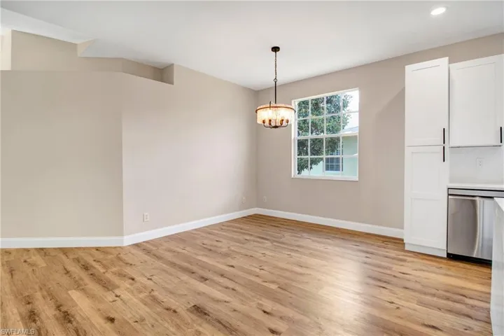 Unfurnished dining area featuring recessed lighting, light wood-style floors, baseboards, and a notable chandelier
