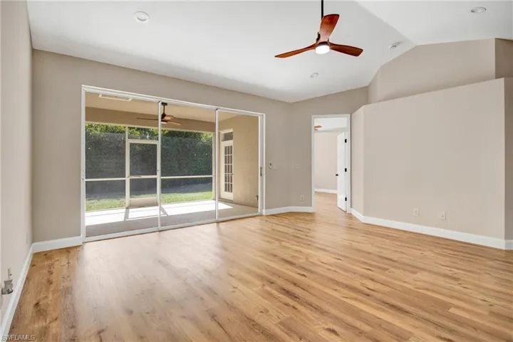 Unfurnished room with light wood finished floors, a ceiling fan, baseboards, and vaulted ceiling