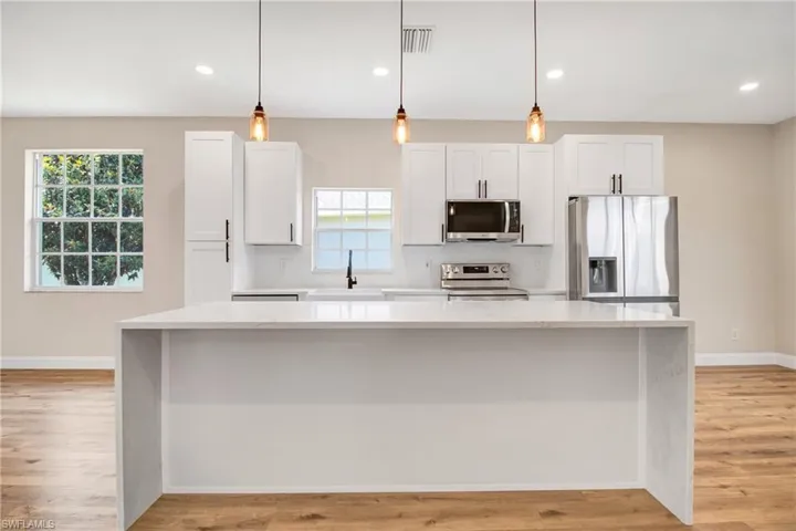 Kitchen featuring stainless steel appliances, light wood-style flooring, a sink, and a healthy amount of sunlight