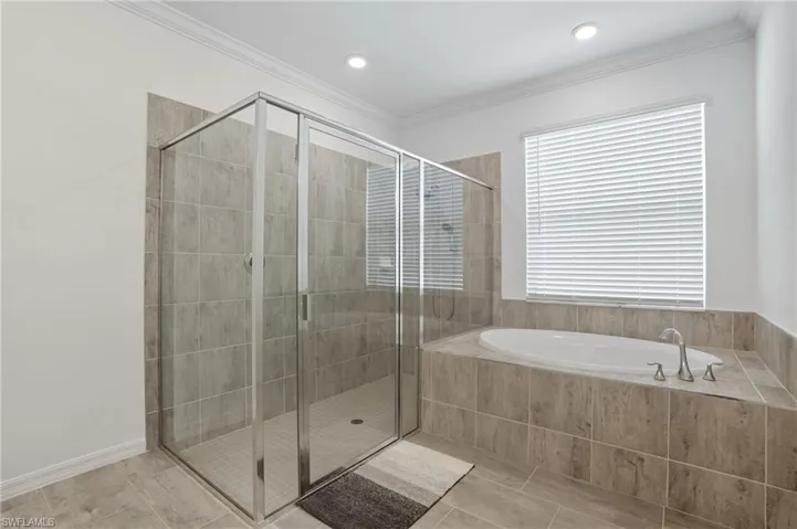 Bathroom with a stall shower, a bath, ornamental molding, and light tile patterned floors