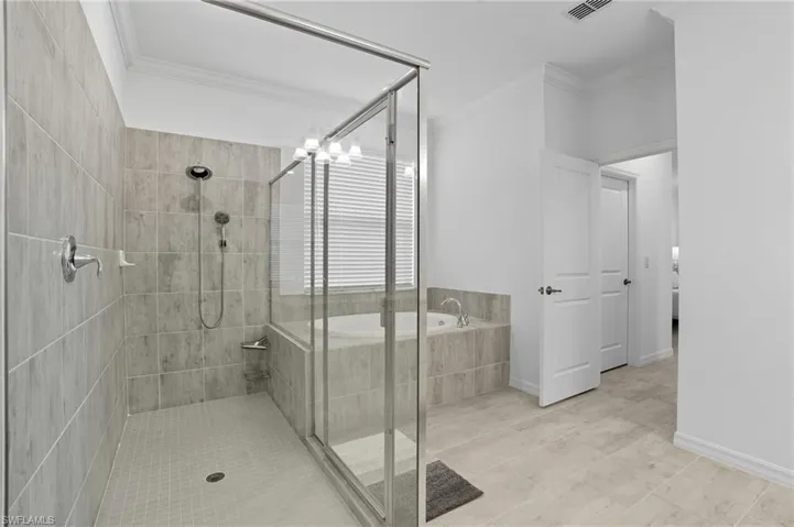 Full bathroom featuring a shower stall, crown molding, a bath, and light tile patterned floors