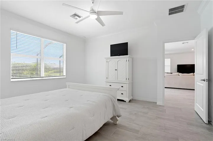 Bedroom featuring crown molding, light wood-style floors, and a ceiling fan