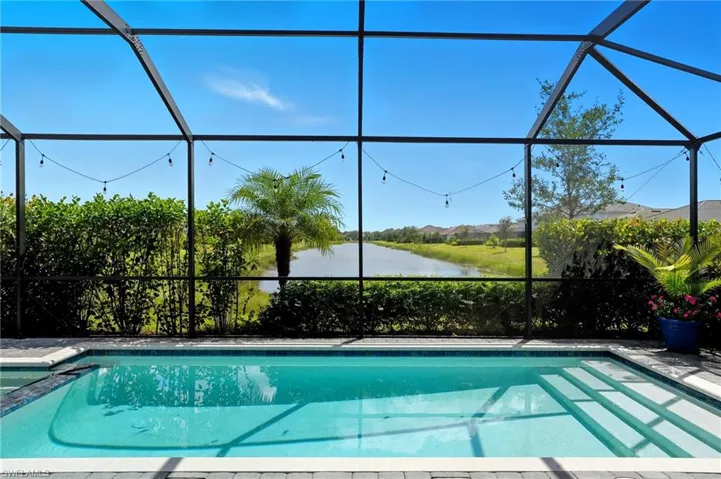 View of swimming pool featuring a sunroom, a lanai, a water view, and a pool with connected hot tub