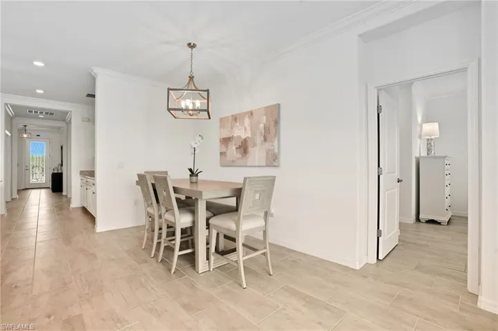 Dining space with ornamental molding, wood finish floors, a chandelier, and recessed lighting
