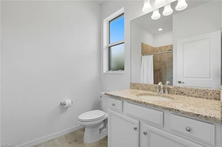 Full bath with vanity, tiled shower, and light tile patterned flooring