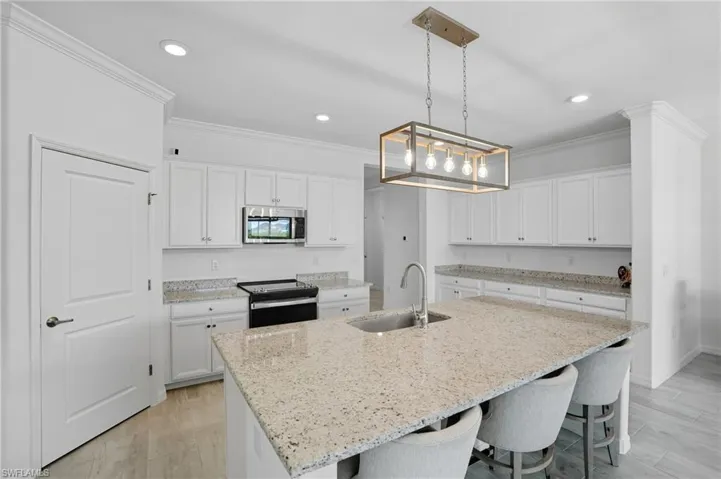 Kitchen featuring crown molding, light wood-style floors, white cabinetry, black electric range, and stainless steel microwave