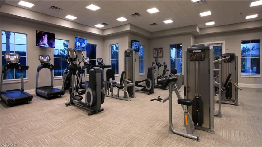 Gym featuring light colored carpet, a drop ceiling, and a tray ceiling