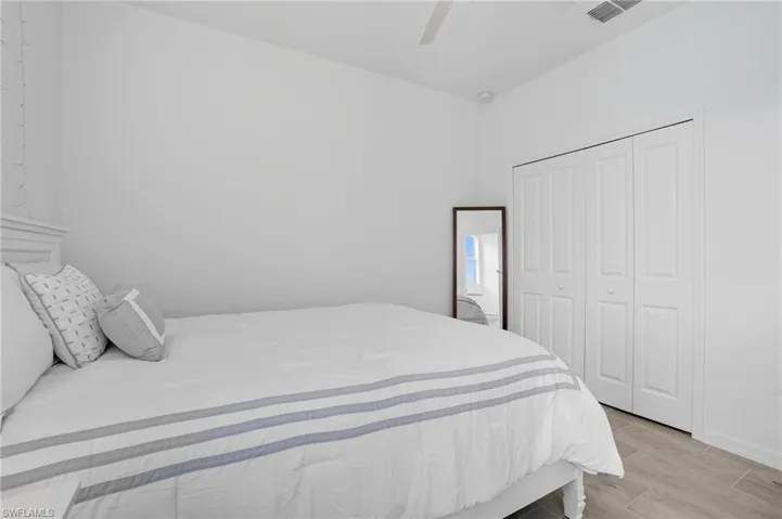Bedroom with wood tiled floors, ceiling fan, and a closet