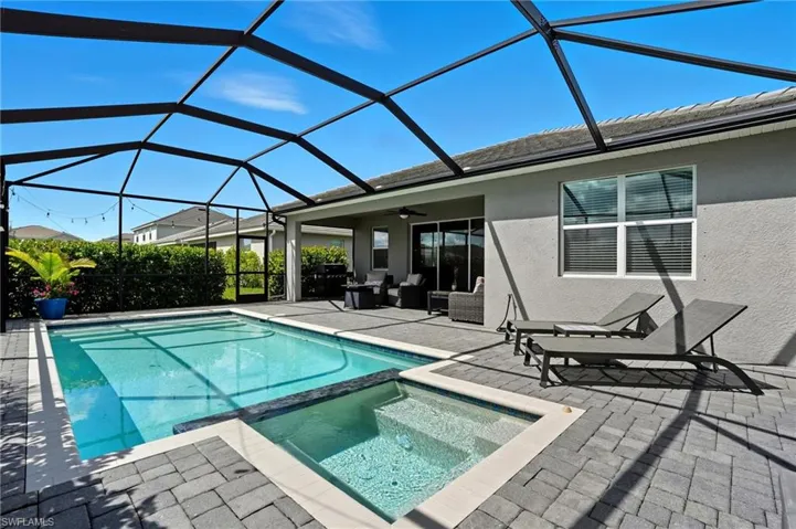 View of pool featuring a sunroom, a pool with connected hot tub, a patio area, a ceiling fan, and glass enclosure