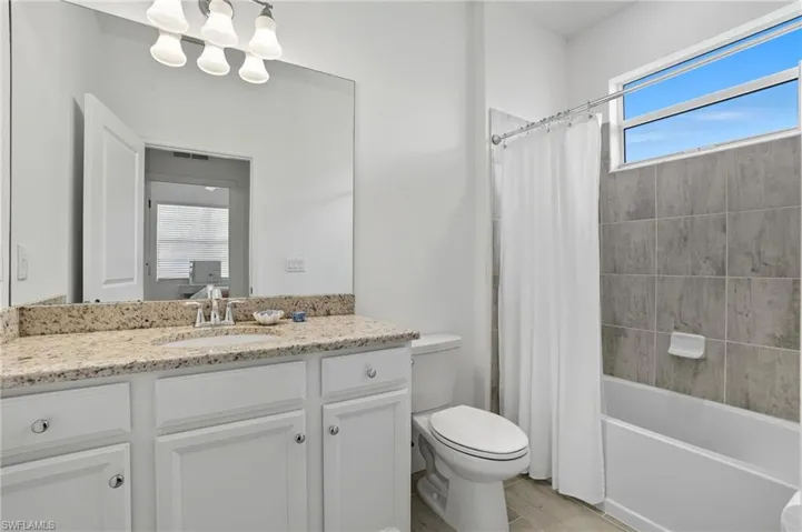 Bathroom featuring shower / bath combination with curtain, vanity, and light wood finished floors