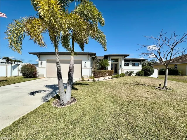 Prairie-style house featuring a front yard, stucco siding, driveway, and a garage
