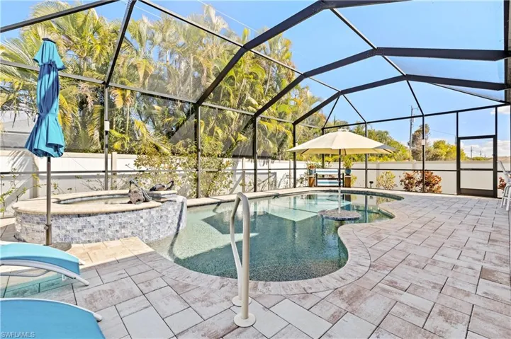 View of swimming pool featuring an in-ground hot tub, glass enclosure, a fenced backyard, and a sunroom