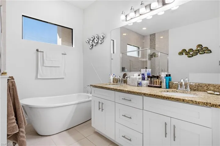 Bathroom with a freestanding bath, double vanity, a stall shower, and light tile patterned floors