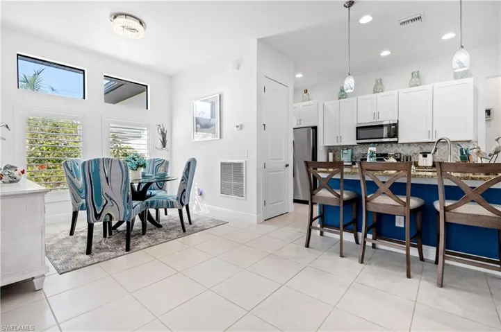 Kitchen featuring decorative light fixtures, two tone cabinetry, stainless steel appliances, light tile patterned floors, and tasteful backsplash