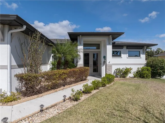 Prairie-style home with stucco siding, a front yard, and french doors