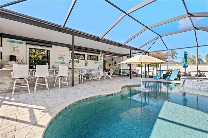View of pool featuring a lanai, patio surround, a sunroom, an in-ground hot tub, and exterior bar