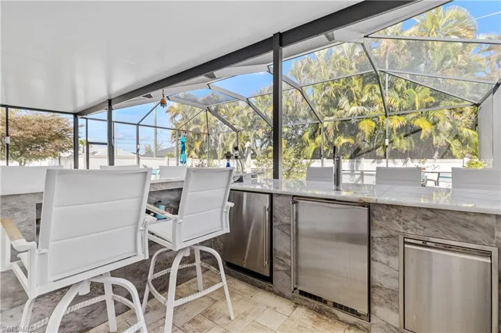 View of patio / terrace featuring a lanai, a sunroom, and an outdoor kitchen