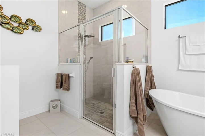 Bathroom featuring a stall shower, light tile patterned floors, and a soaking tub