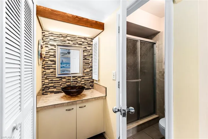 Bathroom featuring vanity, tile patterned floors, toilet, walk in shower, and tasteful backsplash