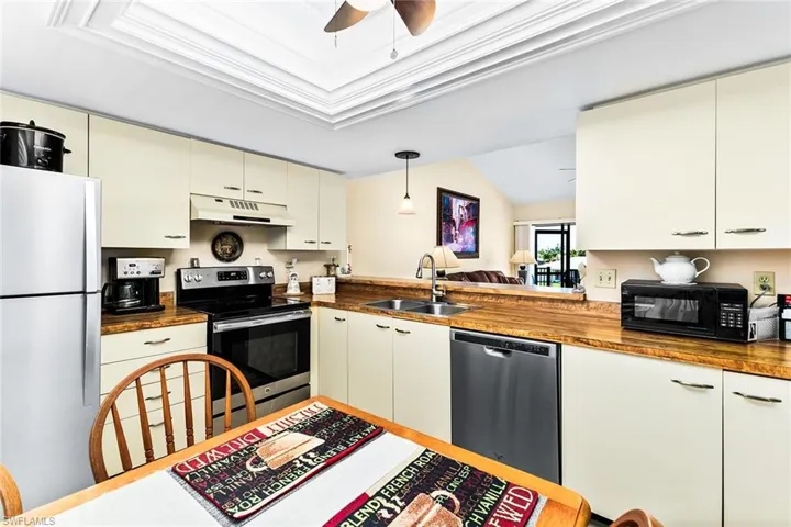 Kitchen featuring sink, hanging light fixtures, ceiling fan, butcher block countertops, and stainless steel appliances