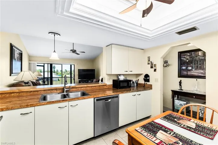 Kitchen featuring sink, hanging light fixtures, wood counters, white cabinets, and appliances with stainless steel finishes