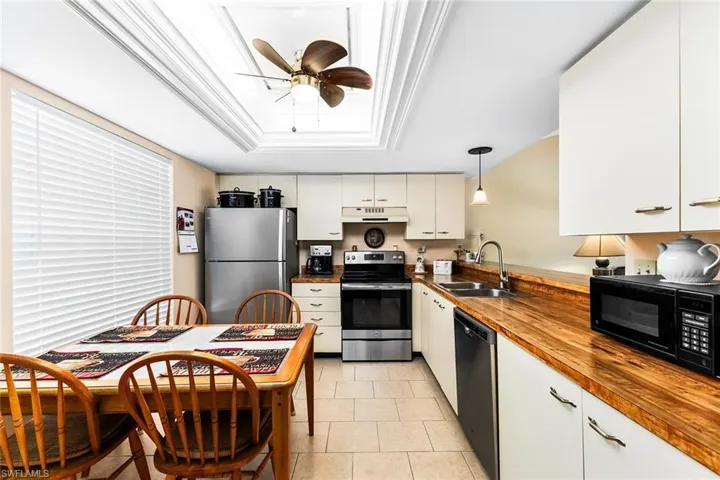 Kitchen featuring sink, hanging light fixtures, wood counters, white cabinets, and appliances with stainless steel finishes