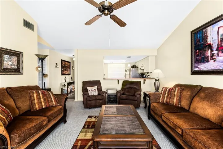 Carpeted living room featuring ceiling fan and high vaulted ceiling