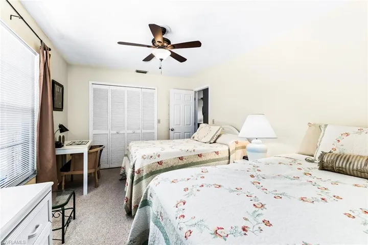 Carpeted bedroom with ceiling fan and a closet