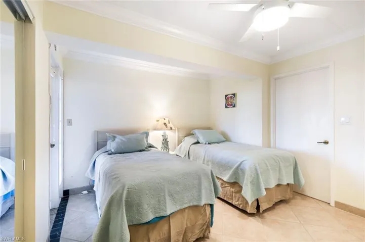 Tiled bedroom featuring a closet, crown molding, and a ceiling fan