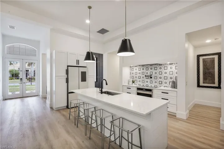 Custom kitchen with white cabinetry, quartz countertops, induction cooktop and pot filler.