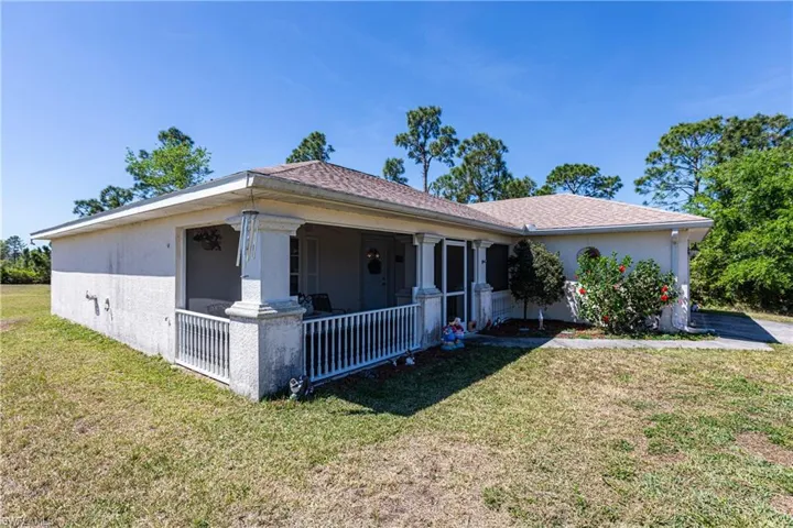 Ranch-style house with a front lawn, stucco siding, and covered porch