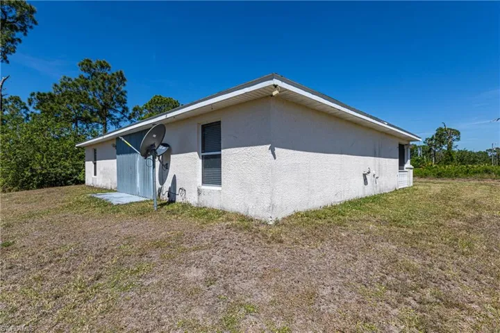 View of side of home with stucco siding and a lawn