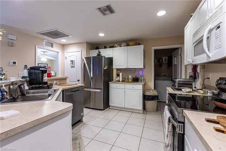 Kitchen with light countertops, a sink, washer / clothes dryer, stainless steel appliances, and visible vents