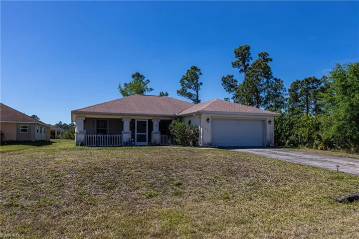 Ranch-style house with covered porch, driveway, a garage, and a front lawn