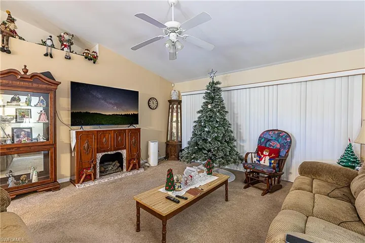 Carpeted living room featuring lofted ceiling and a ceiling fan